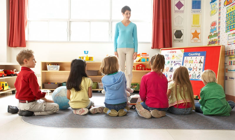 Educatoarea observă copiii în timp ce desenează